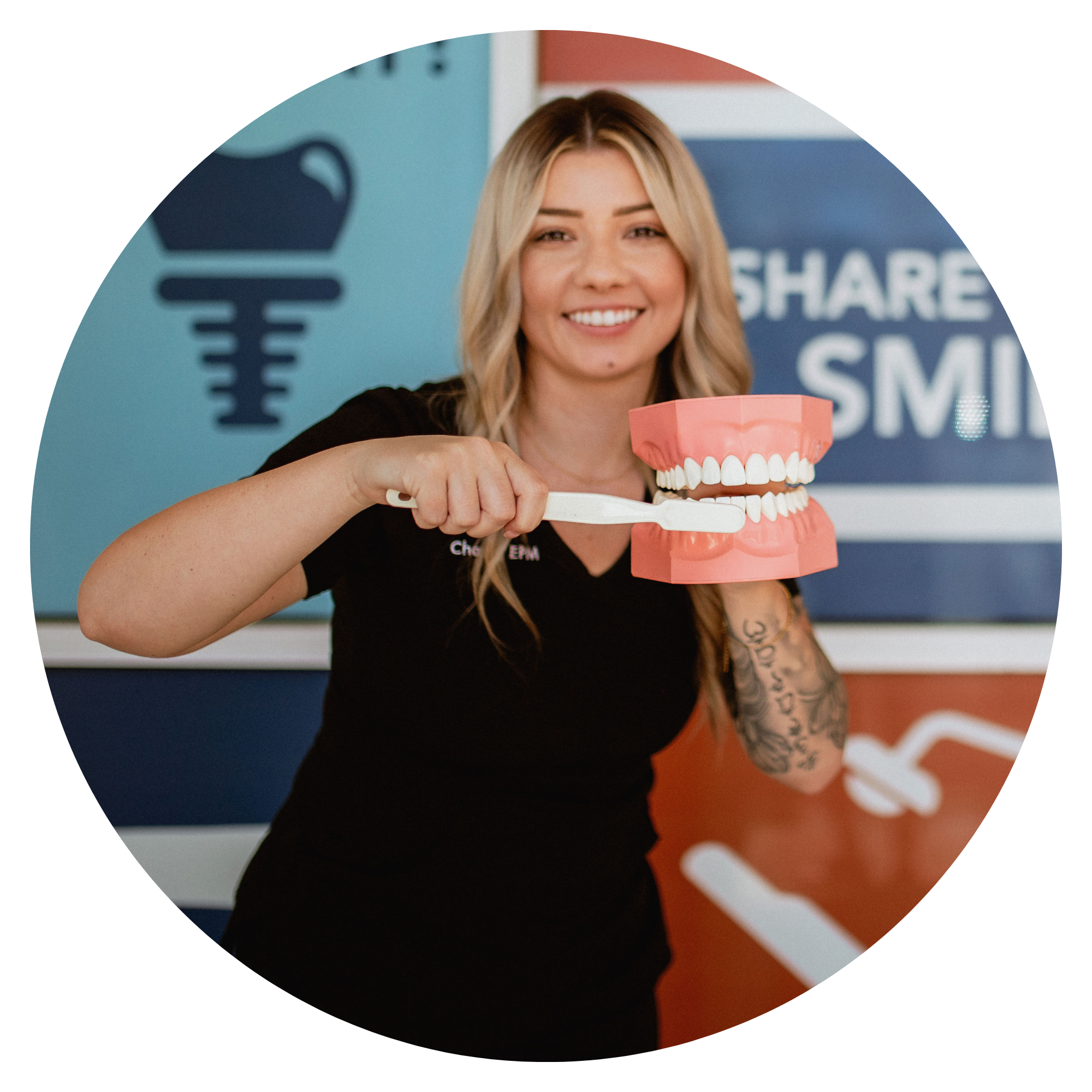 Smiling dental team member in front of Centerpoint Dental holding a toothbrush and dental model to demonstrate proper brushing technique