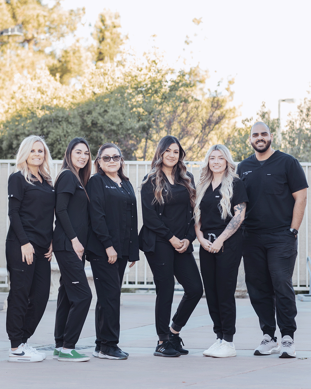 Group photo of the Centerpoint Dental team in Yucaipa, California, standing outdoors in black scrubs and smiling together